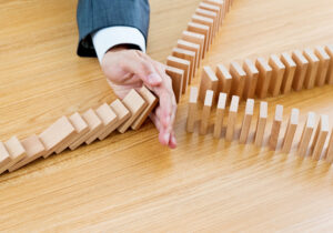 Businessman hand stopping falling blocks on table